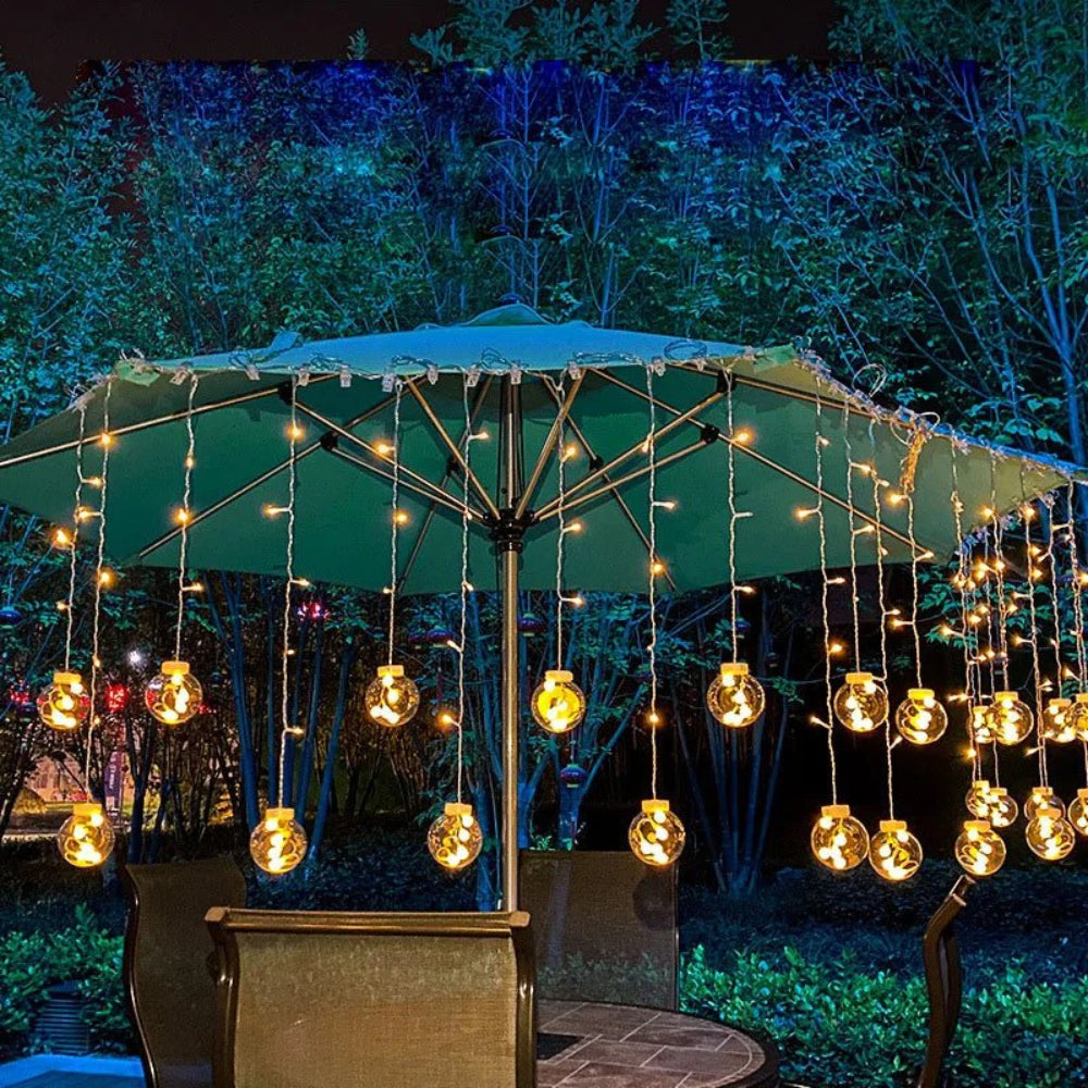 Cortina luminosa con bolas colgantes — ambiente cálido y festivo 